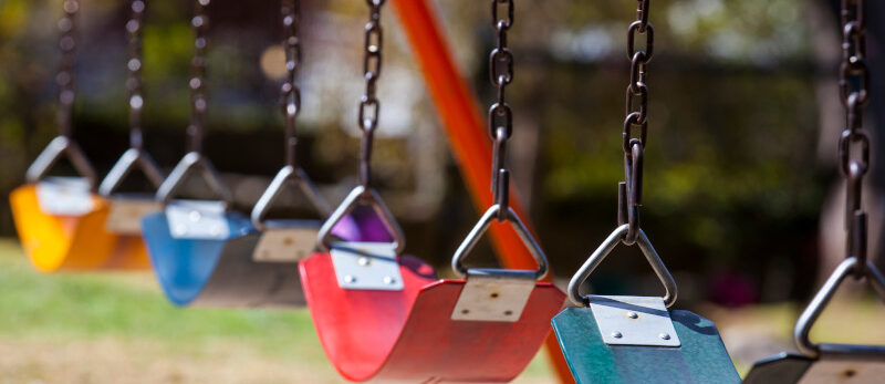 Empty colorful swings at the park Blog - August 2026 - Playground hazards